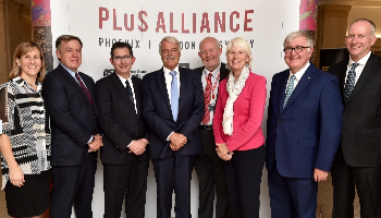 A group of professional men and women, including President Michael Crow, attend a PLuS Alliance event.