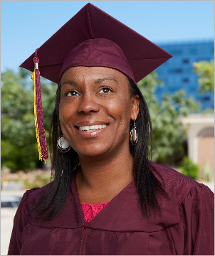 An ASU graduate poses on the Tempe campus wearing graduation regalia.